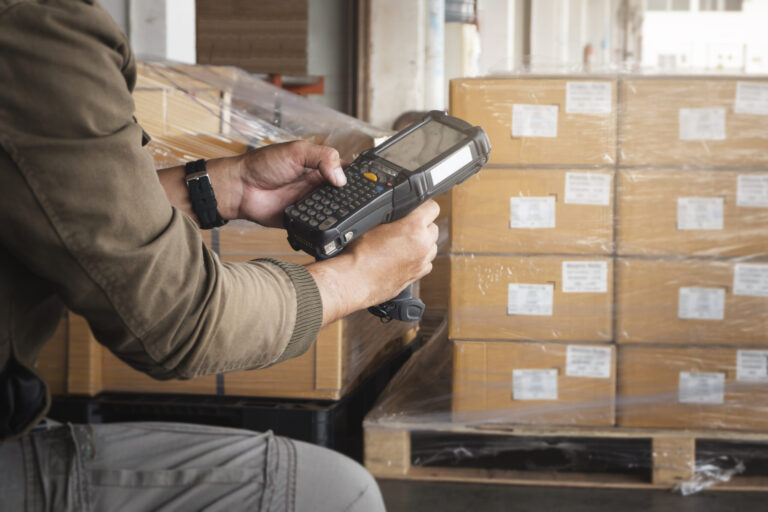 Warehouse worker holding barcode scanner. Computer equipment for warehouse inventory management. Storage warehouse.