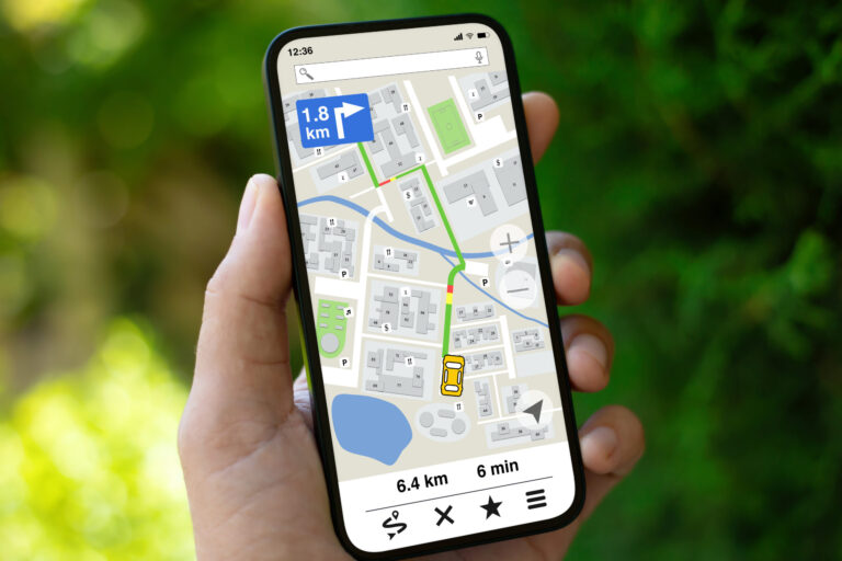 man hand hold phone with navigation application on screen background of green street