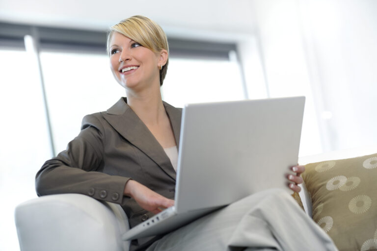 a pretty professional businesswoman working at her laptop on a sofa