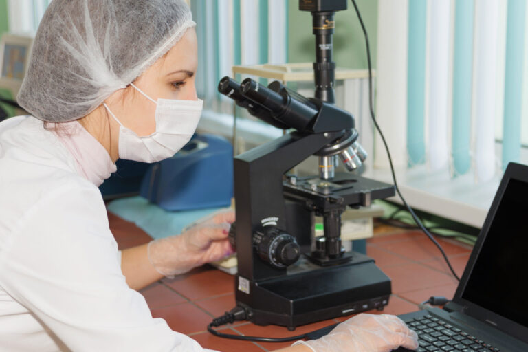 Women scientists exploring the biological sample by modern electron microscope in a laboratory